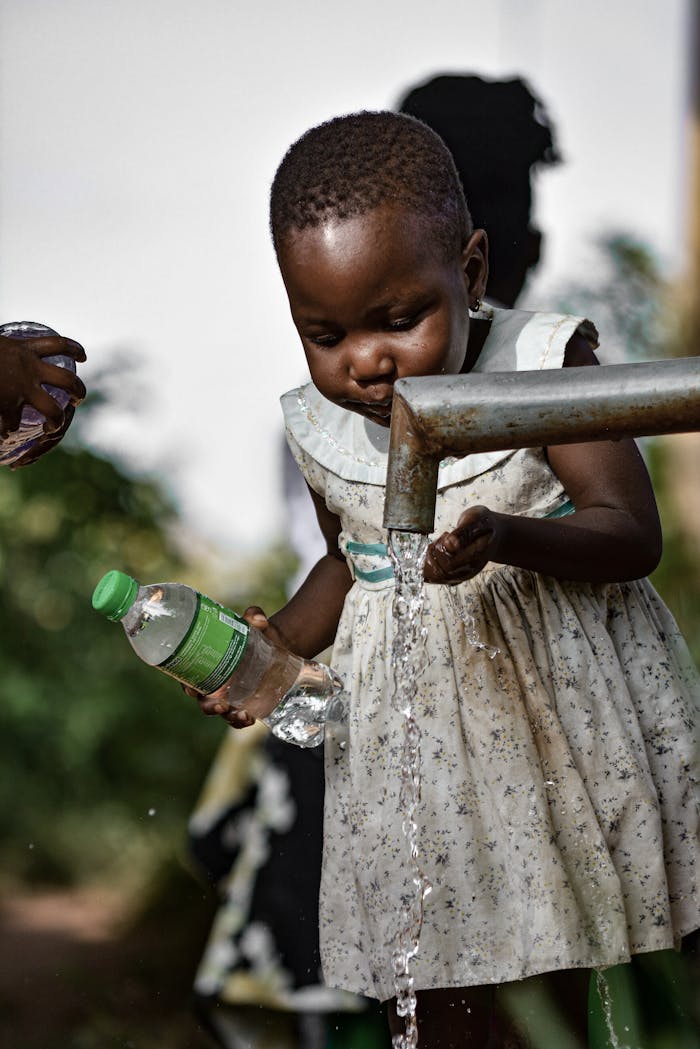 hero-img-01 A young girl collects fresh water from a tap in Kampala, Uganda, ensuring water safety.